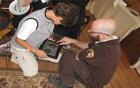 Volunteer and child look at iBook on tablet computer