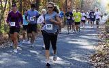 Marathon participants race along a shaded trail.