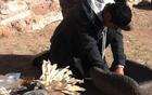 OMK youth grinds corn before making a digital story