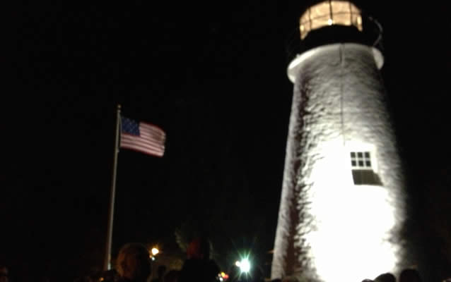 Nightime view of lighthouse with American flag
