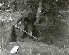 black and white image of a man digging a hole