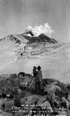 black and white image of a man facing an erupting volcano