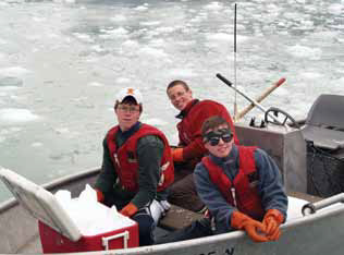 three young men in a boat pulling ice out of the water