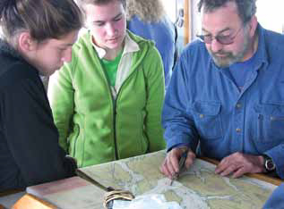 two teens looking at a map with an older man