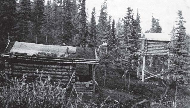 historic black and white image of a log cabin and tall cache