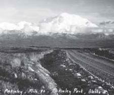 historic image of a dirt road with a huge snowy mountain in the background