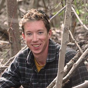 Researcher crouches among trees