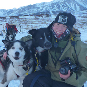 Musher hugs two sled dogs 