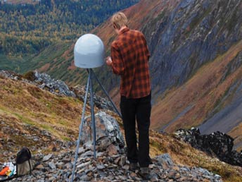 man standing next to a domed device mounted on a tripod