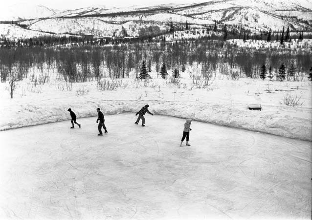 black and white image of four people skating on an ice rink