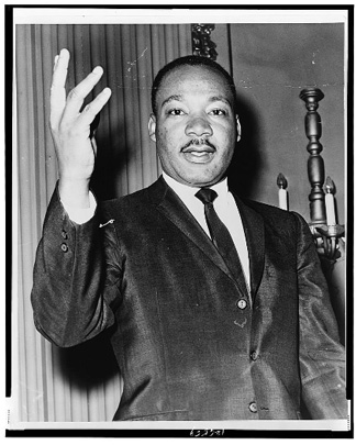 Half-length portrait of Dr. Martin Luther King, Jr., facing front with right arm lifted.