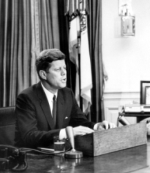 President Kennedy sits at desk, addresses nation