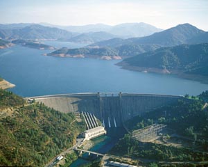 Large view of Shasta Dam surrounded by water and mountains. 