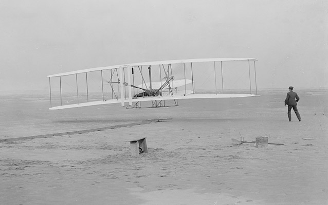 First flight, Orville at the controls, Wilbur running alongside- Kitty Hawk, 1903