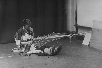A Zuni Ihamana sitting on the floor weaving