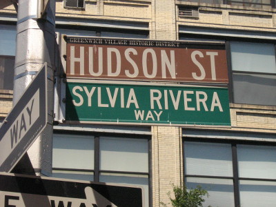 A street sign that says "Hudson St." and "Sylvia Rivera Way"
