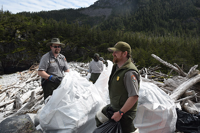 park rangers putting trash into plastic bags