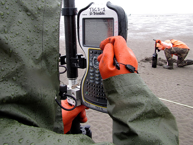 a person in rain gear entering data on a phone-like device