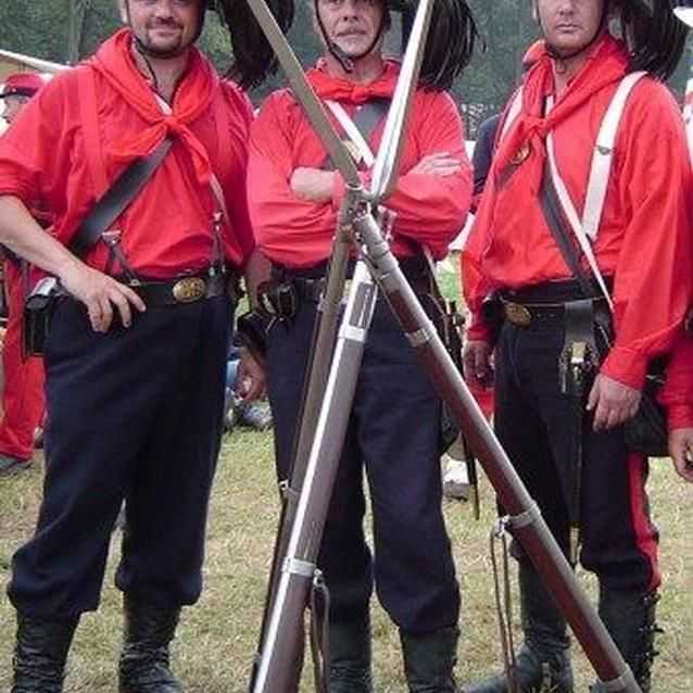 Photo of Garibaldi Guard living historians, in red shirts with black plumed hats.