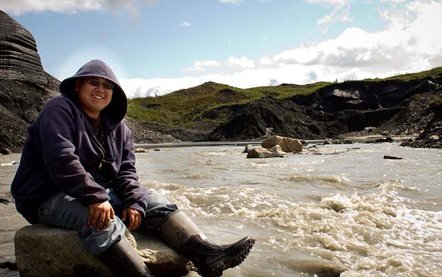 Native Alaskan youth sitting near a river