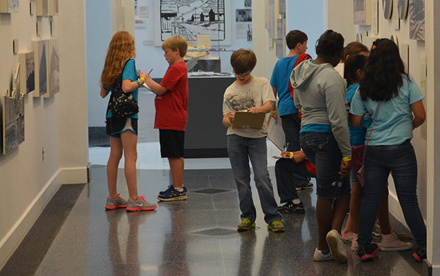 Students work on an activity in the museum hallway.