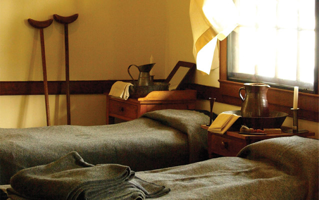 Civil War hospital room with two beds and crutches standing in corner