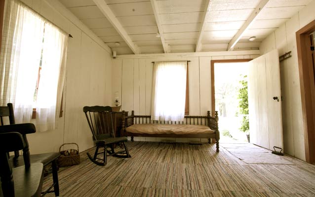 Sparse furnishings of a 19th century cottage include a daybed and rocking chair.
