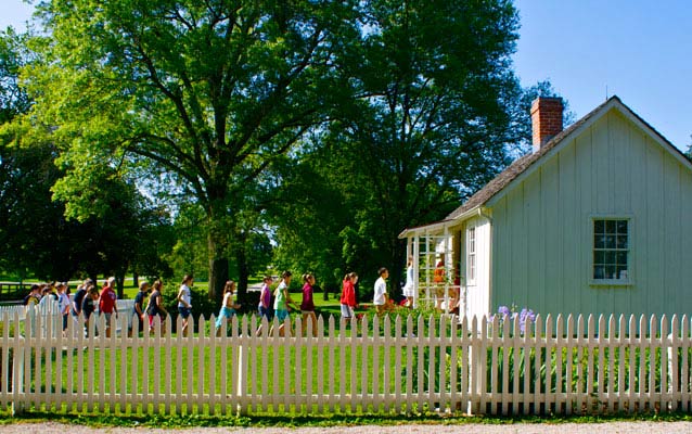 Children line up to visit a two-room historic house.