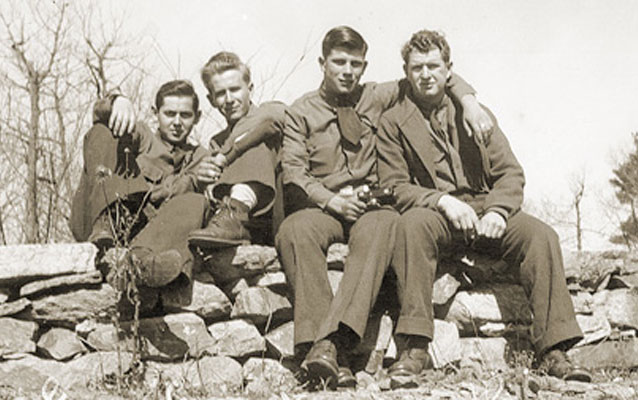 Four CCC boys pictured posing for a photo on a rock wall in Shenandoah National Park