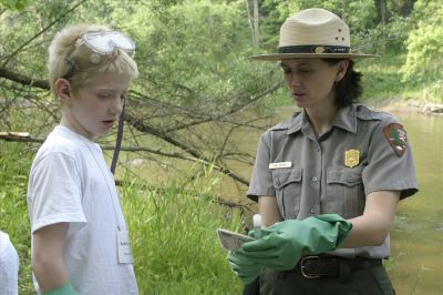 Ranger and boy with blonde hair and goggles standing. Ranger is holding a vile and wearing gloves. Ranger and boy with blonde hair and goggles standing. Ranger is holding a vile and wearing gloves.