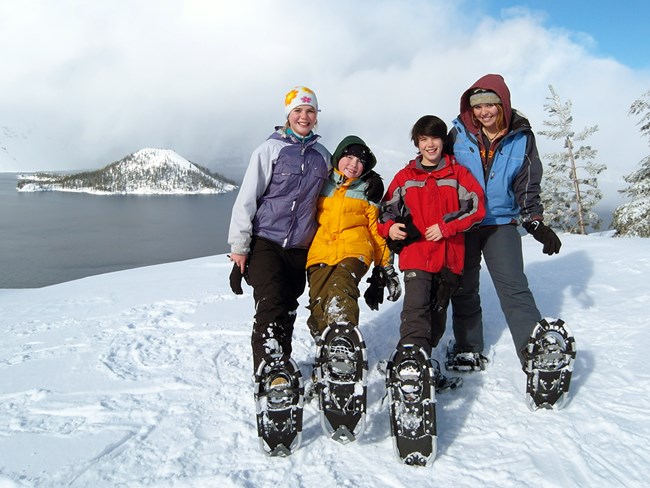 Kids pose in front of Crater Lake on a ranger-guided snowshoe walk.