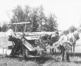 Two men wheat threshing with horse-drawn equipment.