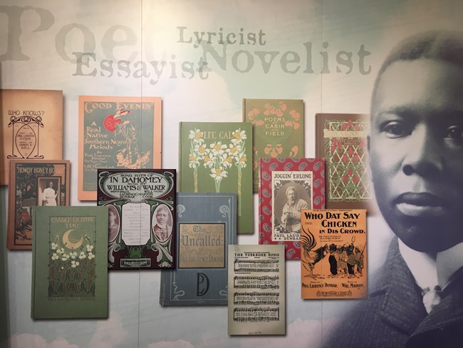 View of exhibits showing Paul Laurence Dunbar's face and several cover illustrations from his various writings.