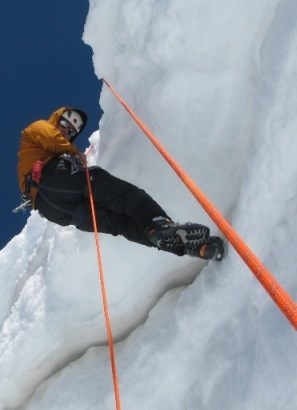 Climber rappelling down a rope into a crevasse