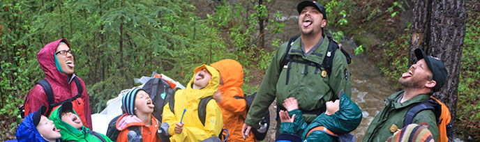 kids and rangers in rain gear stick out their tongues to catch rain drops