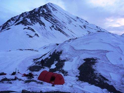 a red tent staked out on a snowy mountainside