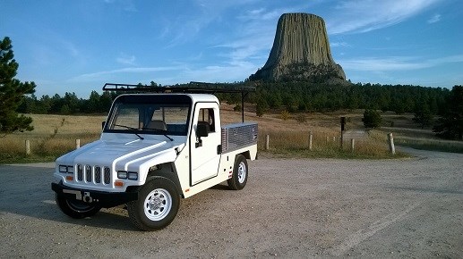 A small white truck with a rock monolith in the background.