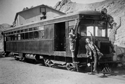 Historic photograph of the Death Valley Railroad engine with two people standing in front of it.