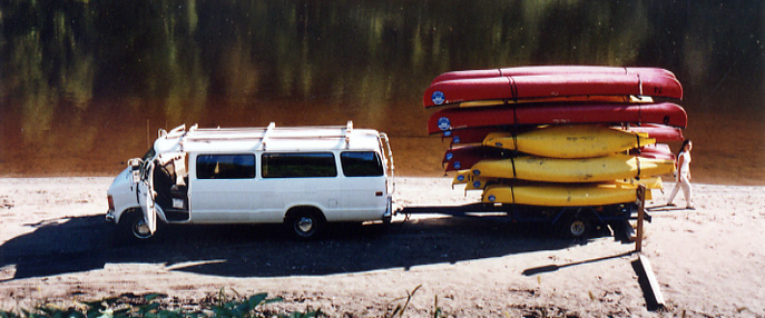Van with canoes on a trailer on a river beach
