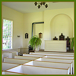 Interior of a wood church with large windows and light walls.