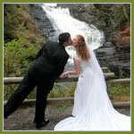Bridal couple kissing in front of a waterfall