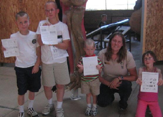 Four kids proudly hold the activity sheets they have completed to become Junior Rangers.