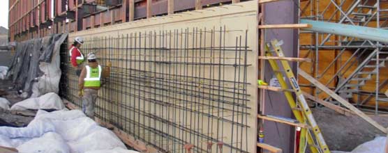 Two men work on rebar that will be part of a concrete grade wall. 