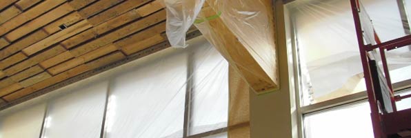 Wood on ceiling beam covered with plastic in preparation for painting walls of visitor center. 