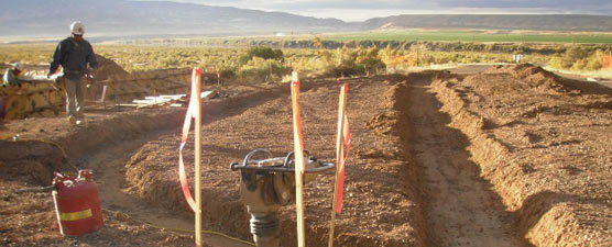 Man walks near shallow ditches excavated for curb and gutter installation.