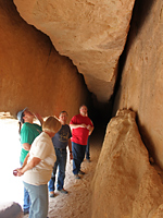 A group of visitors takes a look at the gash in the sandstone known as Whispering Cave.