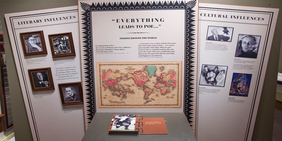 Color photo showing large exhibit signs with an illustrated world map and black and white photos that detail Poe's influence throughout the world.