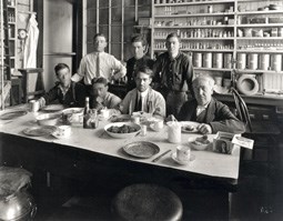 Thomas Edison sitting at a table with his assistants.  They are about to eat a meal.