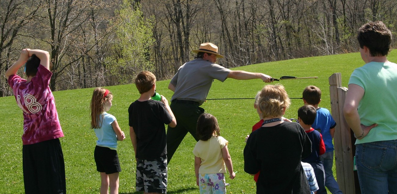 Ranger demonstrating ancient spear throwing device to school children