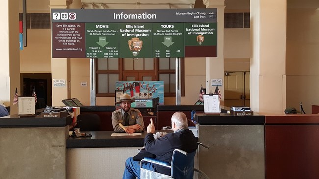 A visitor with a park ranger at the Ellis Island Information Desk